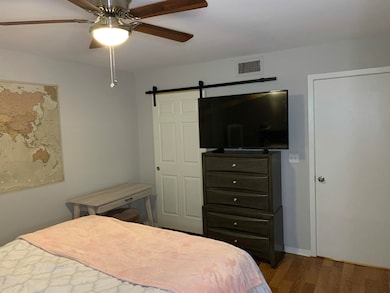 Bedroom featuring a barn door, dark wood-type floo