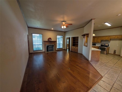 Unfurnished living room with crown molding, light wood-type flooring, ceiling fan, and a fireplace