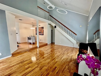 Living area featuring a high ceiling, light wood-type flooring, and stairway