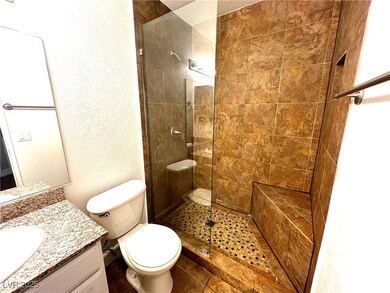 Full bath with a textured wall, a walk in shower, vanity, and dark tile patterned floors