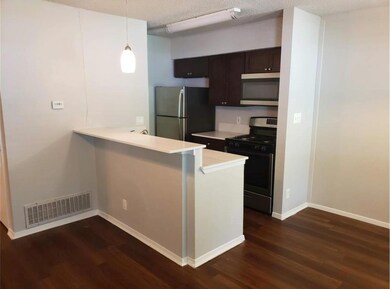 Kitchen with stainless steel appliances, light countertops, dark wood-type flooring, a peninsula, and a textured ceiling