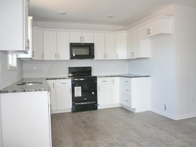12x10 kitchen, white cabinets, grey/black/white swirl granite, black appliances, double stainless sink, brush nickel fixtures, and pulls.