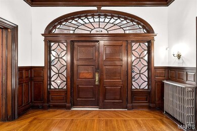 Entrance foyer featuring wainscoting, radiator, a decorative wall, crown molding, and light wood-type flooring