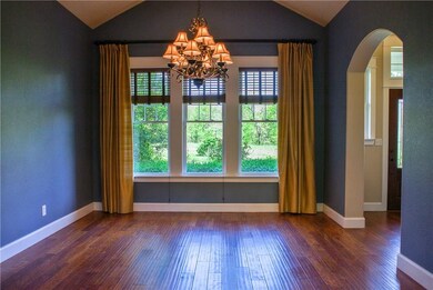 Dining room features rich wood floors, large windows, vaulted ceiling, and arched doorways.