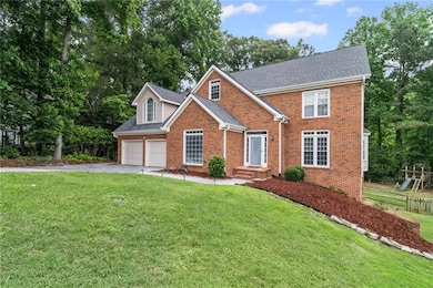 Traditional-style home with brick siding, driveway, an attached garage, and a front yard