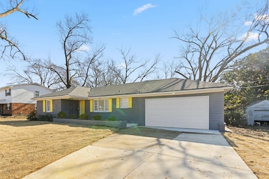 Single story home with a garage and a front lawn