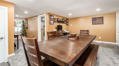 Dining space with light colored carpet and recessed lighting