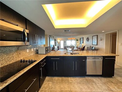 Kitchen with sink, light tile flooring, appliances with stainless steel finishes, kitchen peninsula, and backsplash