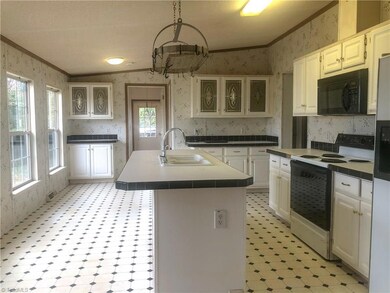 Bright Eat in Kitchen with sink in Island, slide in range, refrigerator and lots of cabinets.