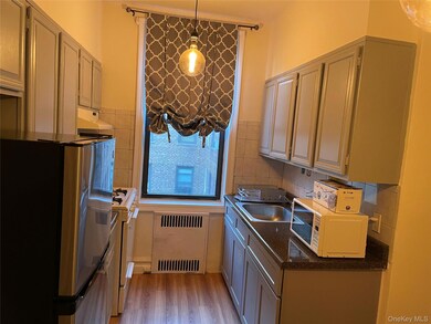 Kitchen with  refrigerator, radiator, light wood-type flooring, white gas range.