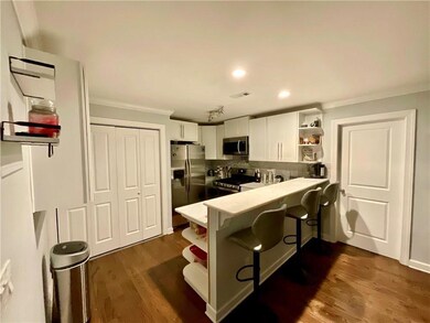 Kitchen with open shelves, dark wood finished floors, white cabinets, a peninsula, and appliances with stainless steel finishes
