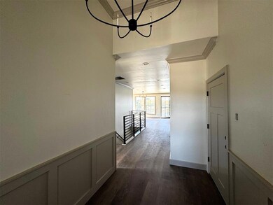 Hallway with wainscoting, a chandelier, a decorative wall, ornamental molding, and dark wood-style flooring