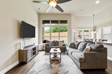 Living room with ceiling fan with notable chandelier and a high ceiling