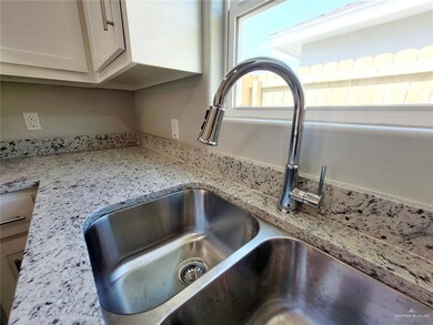 Kitchen view of light stone counters and white cabinets