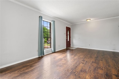 Unfurnished room with wood finished floors, ornamental molding, a textured ceiling, and baseboards
