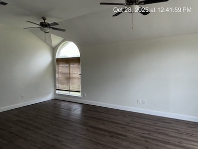 Empty room featuring dark wood finished floors, lofted ceiling, and ceiling fan