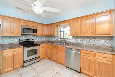 Kitchen featuring backsplash, sink, appliances with stainless steel finishes, a textured ceiling, and ceiling fan