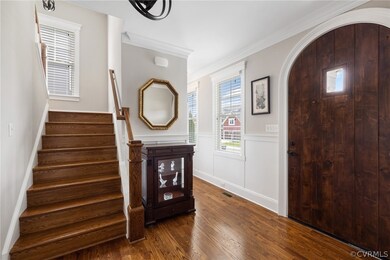 Entrance foyer featuring crown molding and dark wo