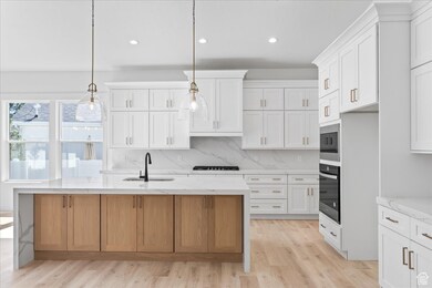 Kitchen with black appliances, a sink, white cabinetry, light wood-type flooring, and recessed lighting