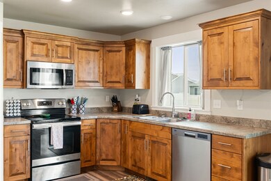 Kitchen with stainless steel appliances, brown cabinetry, light countertops, wood finished floors, and recessed lighting