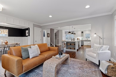 Bright and open, the living room connects effortlessly with the kitchen and dining spaces, featuring refined millwork, recessed lighting, and timeless craftsmanship.