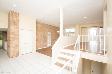 Stairs featuring tile patterned flooring, recessed lighting, brick wall, and a chandelier