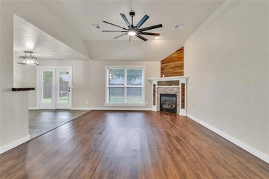 Unfurnished living room with dark wood-style flooring, a fireplace, high vaulted ceiling, a ceiling fan, and a textured wall