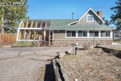 View of front with stone siding, a sunroom, gated fence to backyard