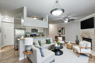 Living area featuring ornamental molding, light wood-style floors, a tiled fireplace, and ceiling fan