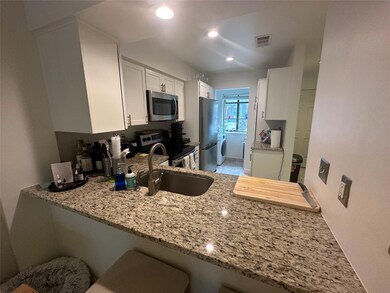 Kitchen with light stone counters, a sink, stainl