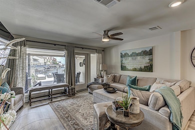 Living room with light wood finished floors, a ceiling fan, and a textured ceiling