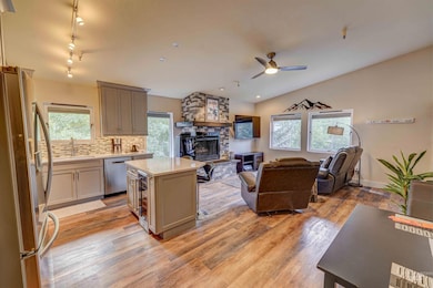 Kitchen featuring stainless steel appliances, backsplash, open floor plan, healthy amount of natural light, and light wood finished floors