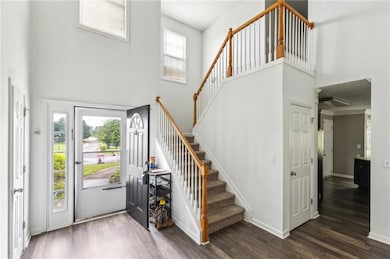 Foyer entrance with a high ceiling, stairway, wood
