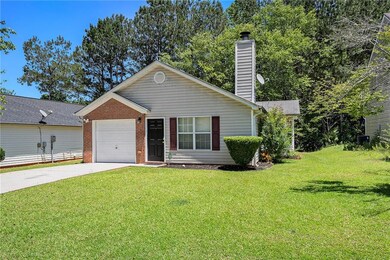 Ranch-style home featuring concrete driveway, an attached garage, a front yard, and a chimney