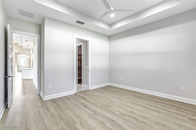 Unfurnished bedroom featuring a tray ceiling, light wood-type flooring, a ceiling fan, and recessed lighting