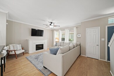 The family room features crown molding, a ceiling fan with light, and a built-in electric  heat producing fireplace. Three windows with automatic blinds and decorative drapes fill the space with natural light.