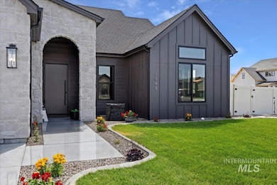 View of front of house with board and batten siding, a gate, stone siding, and roof with shingles