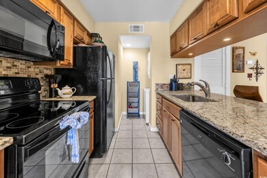 Kitchen with black appliances, a sink, brown cabinets, and decorative backsplash