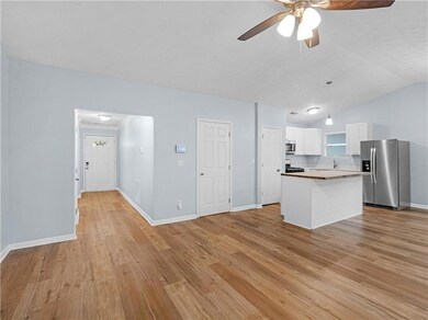 Kitchen featuring stainless steel appliances, light wood-style flooring, white cabinetry, a ceiling fan, and hanging light fixtures