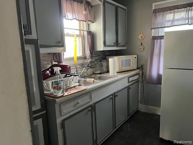 Kitchen with decorative backsplash, white appliances, light countertops, and gray cabinetry