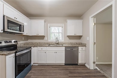 Kitchen featuring sink, white cabinetry, dark hard