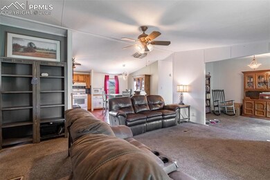 Carpeted living room with ceiling fan and vaulted ceiling