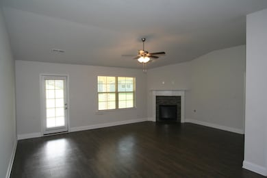 Unfurnished living room with vaulted ceiling, dark wood-style floors, ceiling fan, and a fireplace