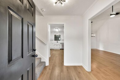 Entry foyer featuring light wood-type flooring, crown molding, stairs, and baseboards