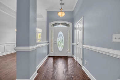 Foyer entrance featuring dark wood finished floors, crown molding, and a towering ceiling