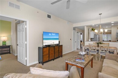 Living area featuring visible vents, light colored carpet, and ceiling fan with notable chandelier