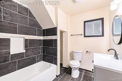 Bathroom with vanity, dark tile patterned floors, and bathing tub / shower combination