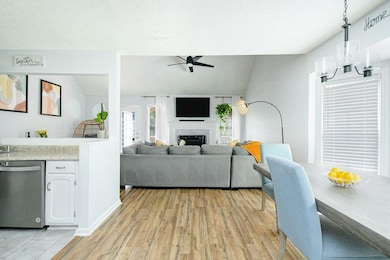 Living area featuring ceiling fan, lofted ceiling, a fireplace, light wood finished floors, and a textured ceiling