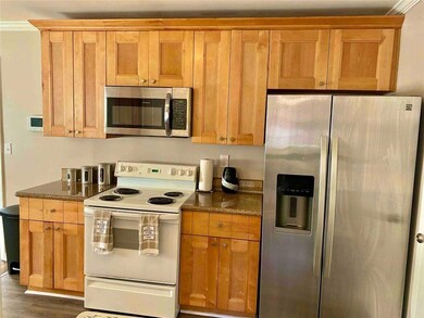 Kitchen with stainless steel appliances, dark wood-style flooring, and dark stone counters