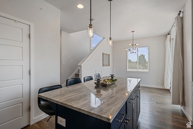 Kitchen with a breakfast bar, decorative light fixtures, dark wood finished floors, a center island, and a textured ceiling